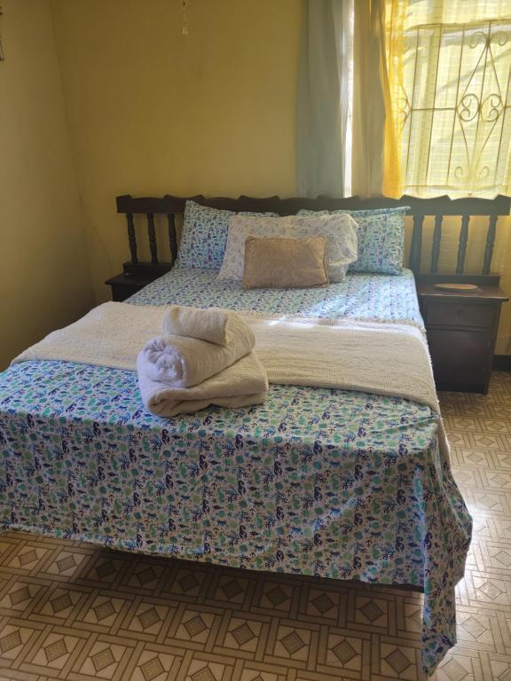 a bed with a towel laying on top of it at Graeme Hall- 1 Bedroom 1 Bath With Shared Kitchen in Christ Church