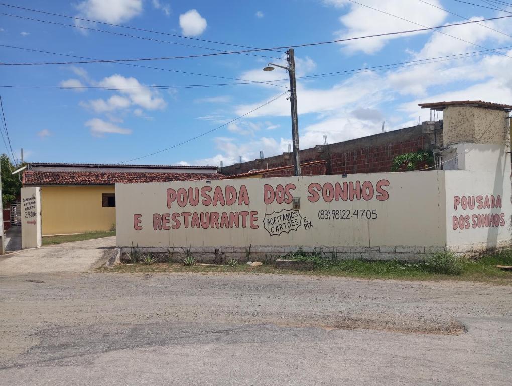 Una pared con un cartel que lee pueblo perro somos y restaurante en Pousada Dos Sonhos e Restaurante en Tacima