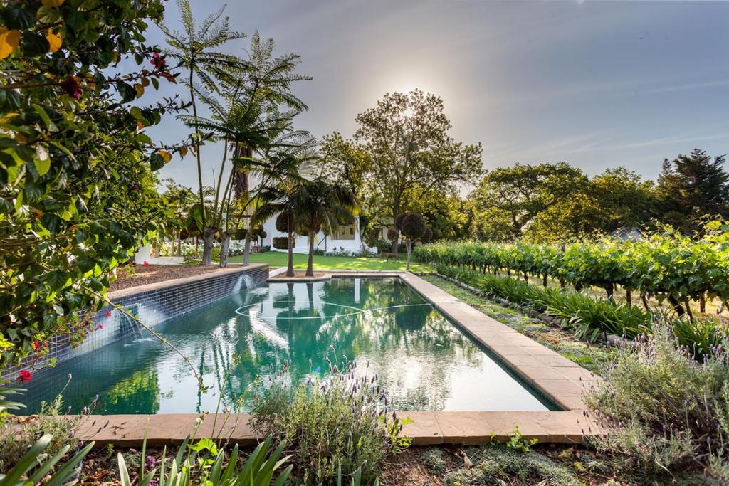 una piscina en medio de un jardín en Nabygelegen Gate house, en Bainʼs Kloof