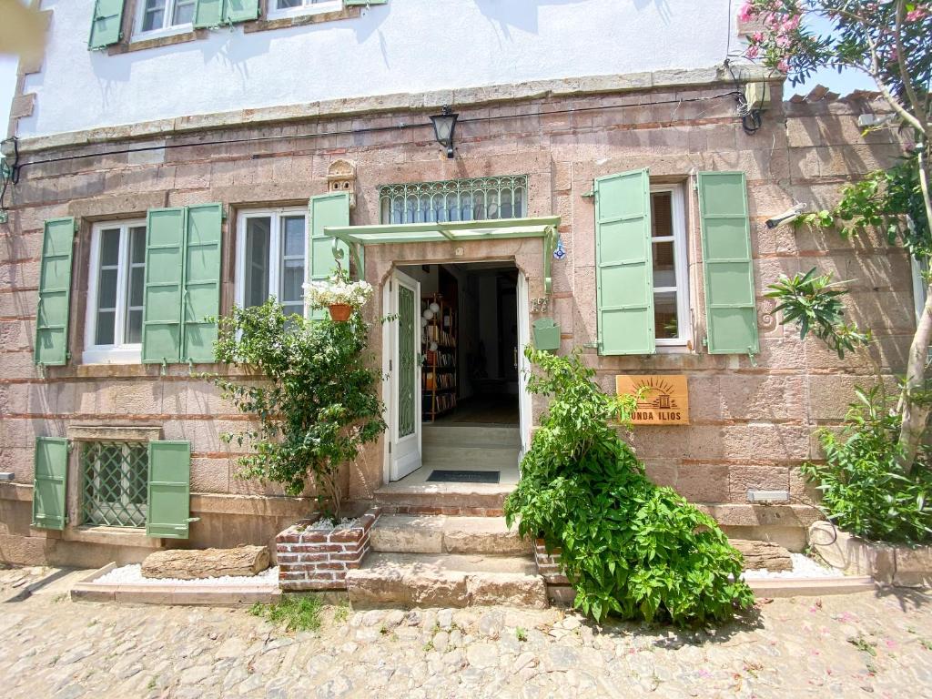 una antigua casa de ladrillo con persianas verdes en Cunda Ilios Hotel, en Ayvalık