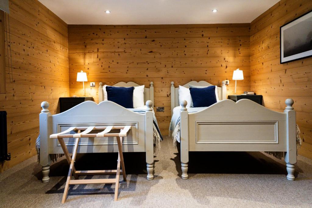 two beds in a room with wooden walls at The Hayloft at Lower Hurst Farm in Hulme End