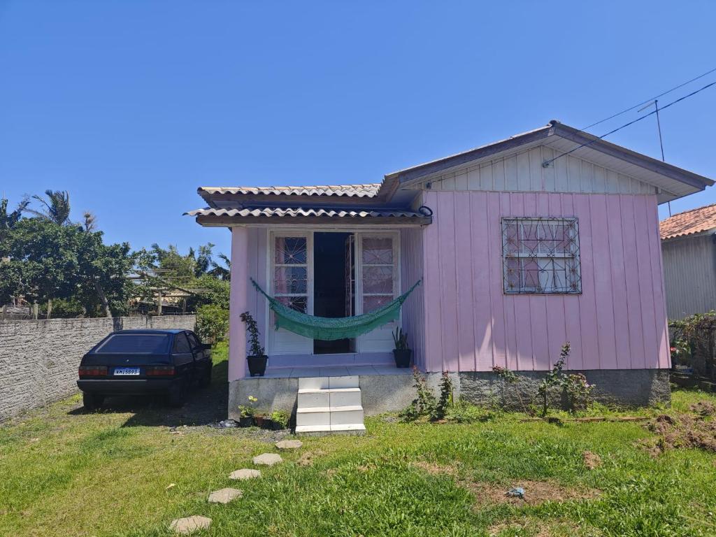 ein rosafarbenes Haus mit einem davor geparkt in der Unterkunft Casa inteira Balneário Rincão in Balneário Rincão