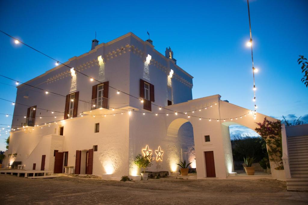 um edifício branco com luzes acesas à noite em Masseria Torre Coccaro em Savelletri di Fasano