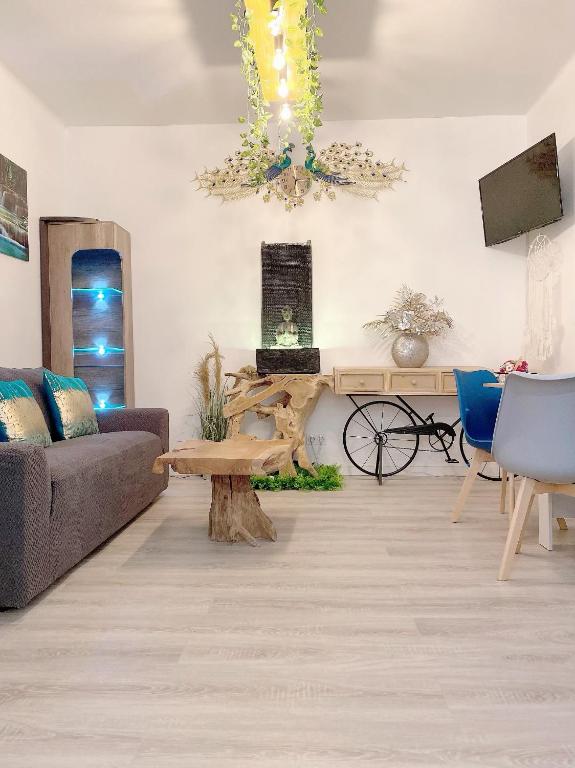 ein Wohnzimmer mit einer Couch und einem Kronleuchter in der Unterkunft Charmant et moderne de L’Hay in LʼHay-les-Roses