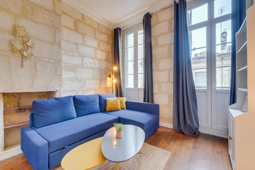 un salon avec un canapé bleu et une table dans l'établissement Le Bon Pasteur - Joli T2 Place de la Victoire, à Bordeaux