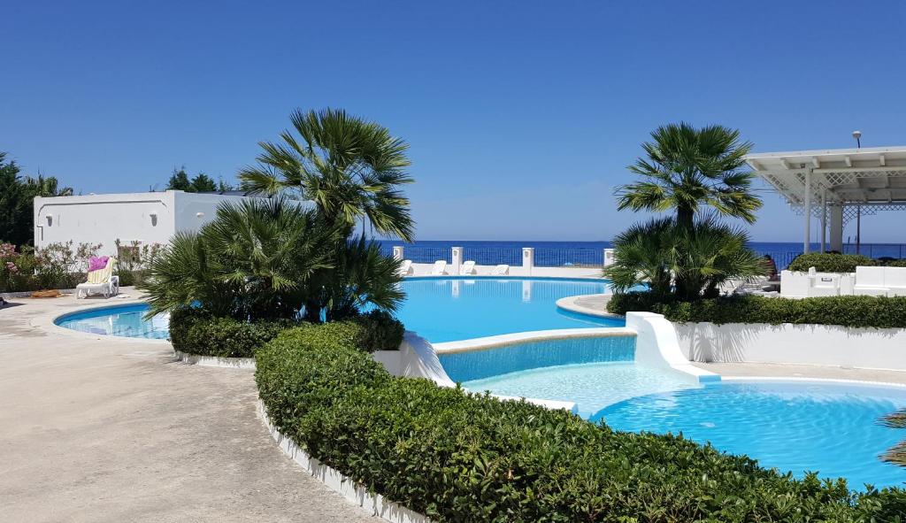 a pool with palm trees and the ocean in the background at Residence Il Cicero in Porto San Giorgio