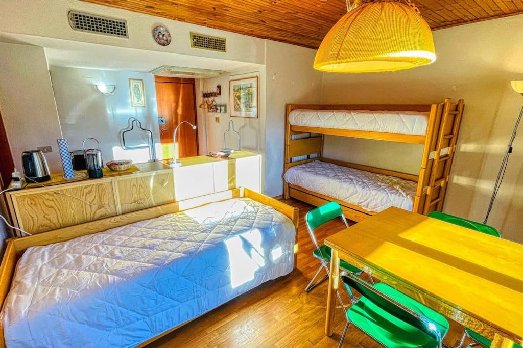 a bedroom with two beds and a table and a dining room at Appartamento La Chapelle Chaberton - Affitti Brevi Italia in Sauze dʼOulx