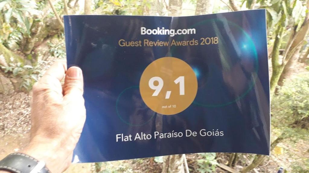 a person holding up a sign in front of a forest at Flat Alto Paraíso De Goiás 9,1 in Alto Paraíso de Goiás