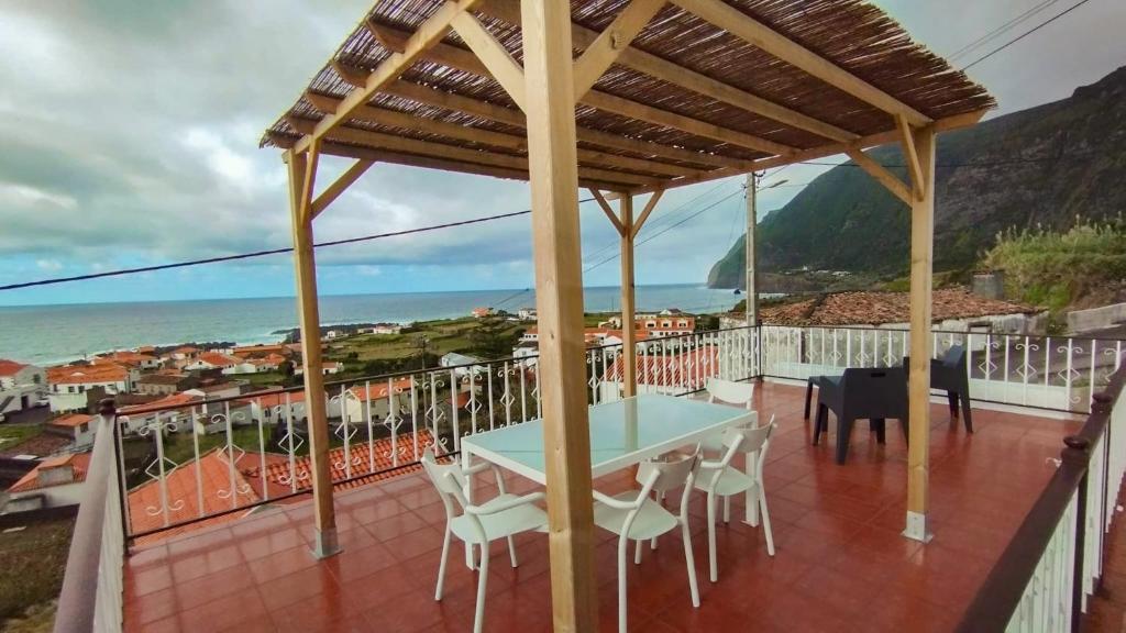 a table and chairs on a balcony with a view of the ocean at CASA do PÁTIO in Faja Grande
