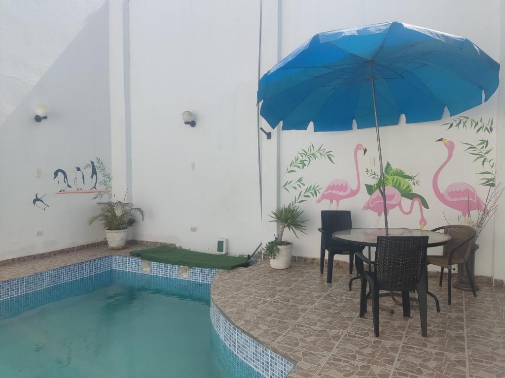 a table and chairs with an umbrella next to a pool at Hospedaje El Candelabro de Paracas in Paracas
