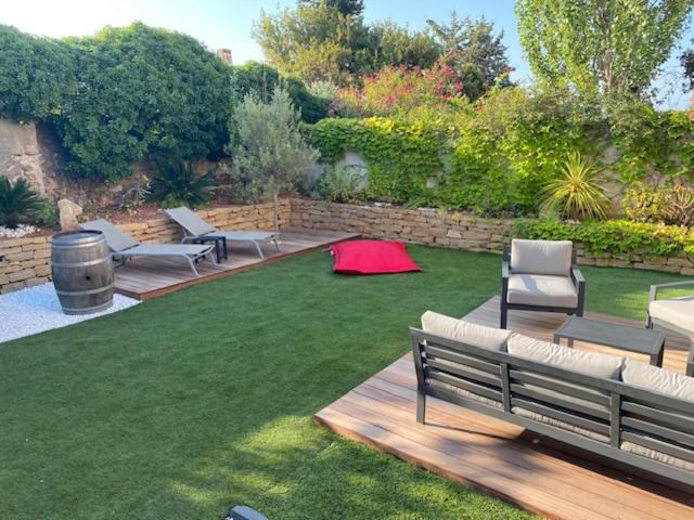 un jardin avec des bancs et une pelouse avec un tapis rouge dans l'établissement Le jardin de Flo à Bandol, à Bandol