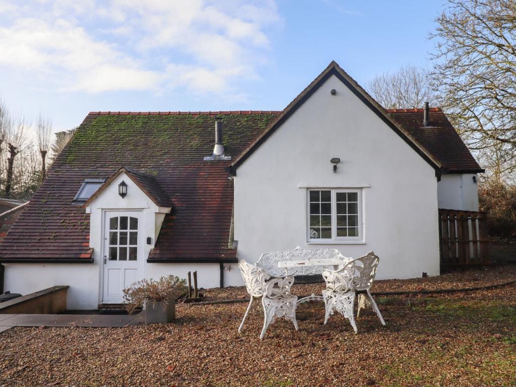 een tafel en stoelen voor een wit huis bij The Little White Cottage in Chipping Norton