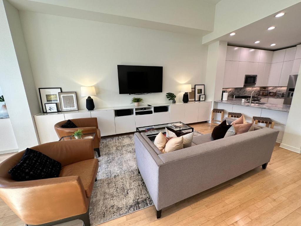a living room with two couches and a flat screen tv at Old Town Pied-a-Terre with Private Terrace and Parking! in Chicago