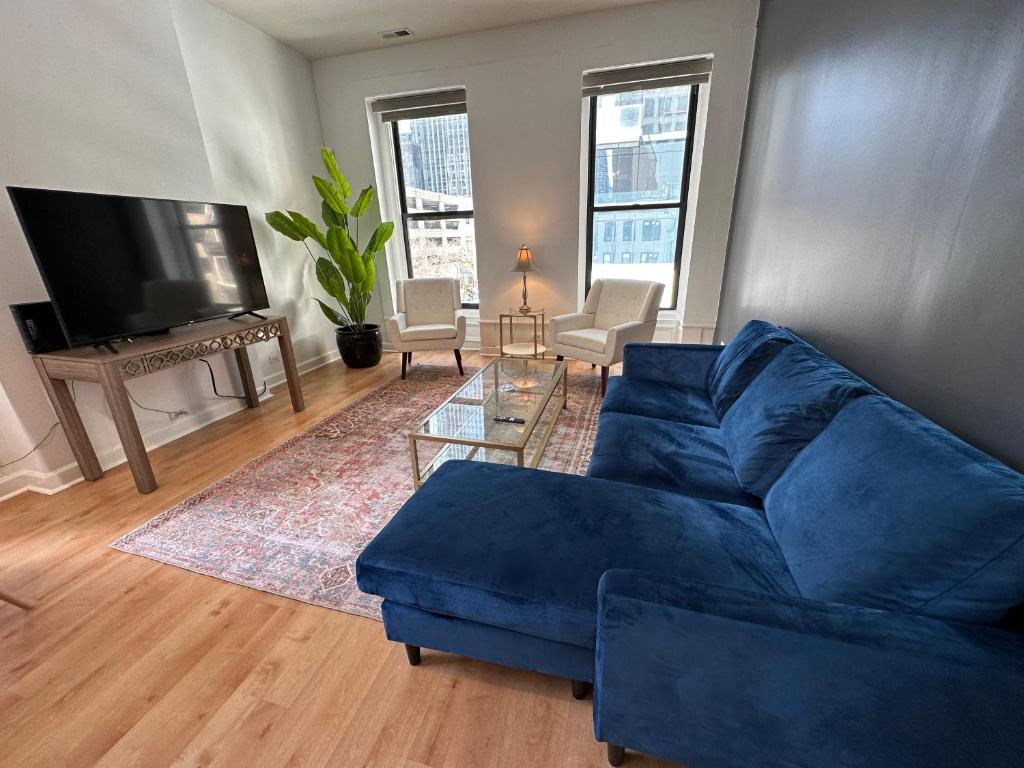 a living room with a blue couch and a television at River North Hideaway with Amazing Views and Parking in Chicago