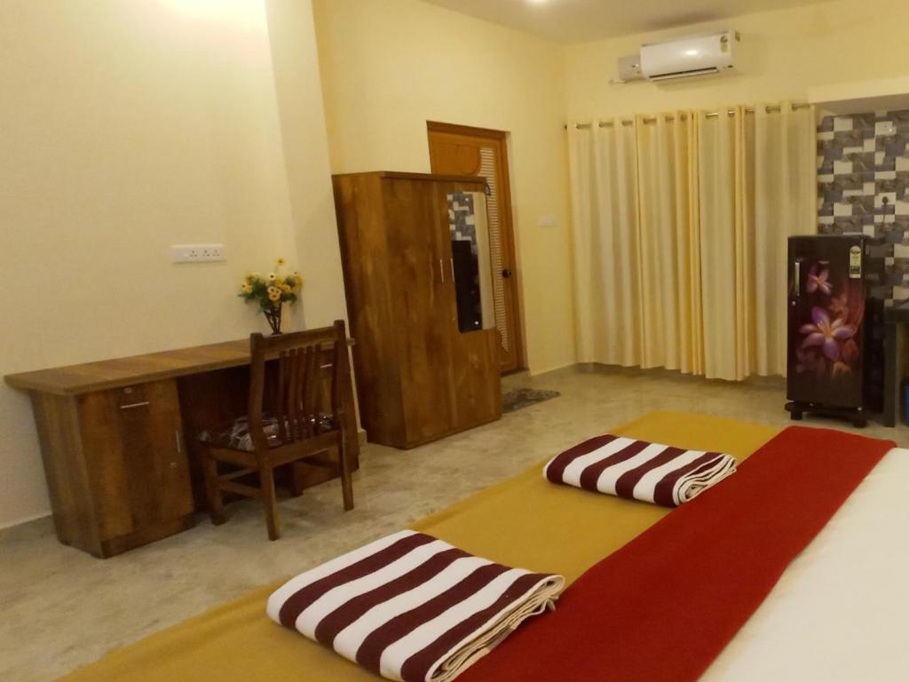 een slaapkamer met 2 bedden, een bureau en een stoel bij SAI HOMESTAY in Agonda