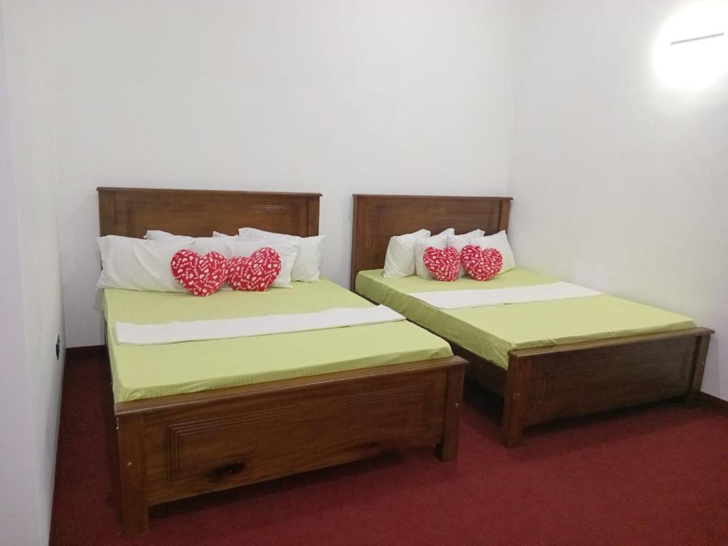 - 2 lits avec des oreillers rouges dans une chambre dans l'établissement Idom Cozy, à Gampola