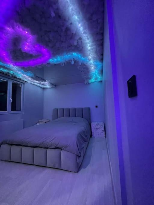 a bedroom with a bed and purple lights on the ceiling at L'Oasis Étoilée in Chelles