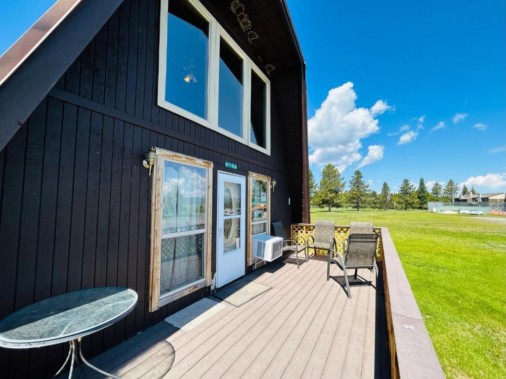 ein schwarzes Haus mit einer Terrasse mit einem Tisch und Stühlen in der Unterkunft Hole-In-1 Yellowstone Getaway - Sleeps 6 in Rea