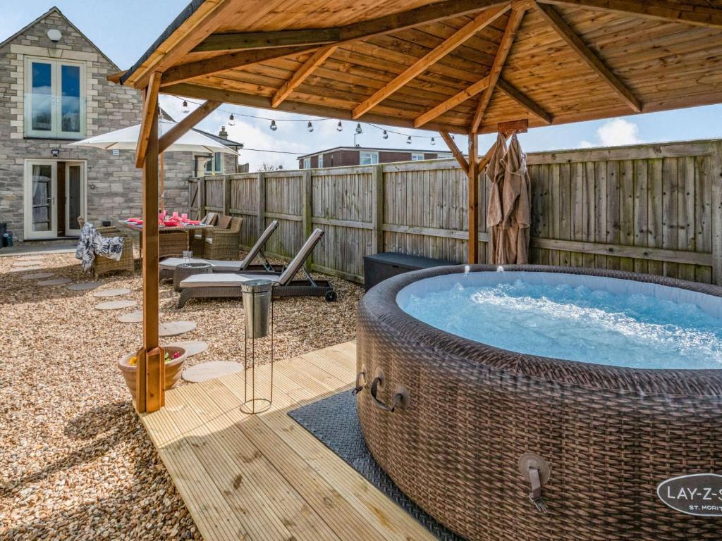 a hot tub with a wooden umbrella on a patio at 2 bed property in Bradford-on-Avon 87056 in Southwick