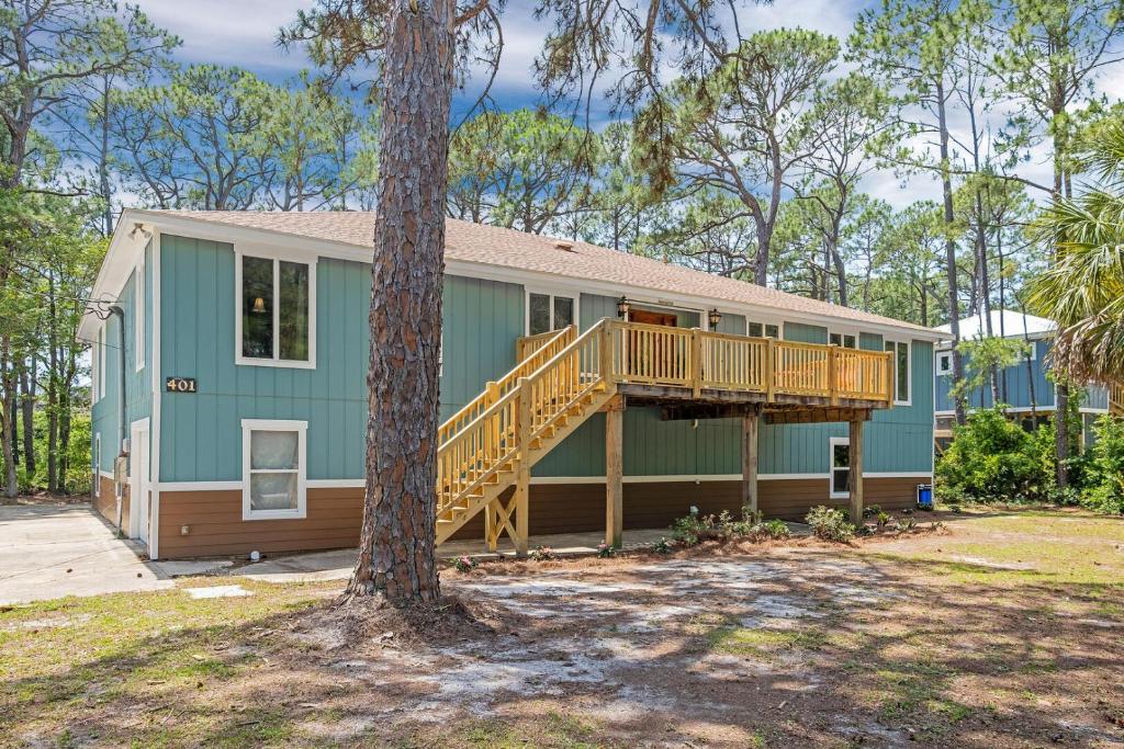 a green house with a deck and a tree at 086 DI Big House - 6 Bedrooms in Dauphin Island