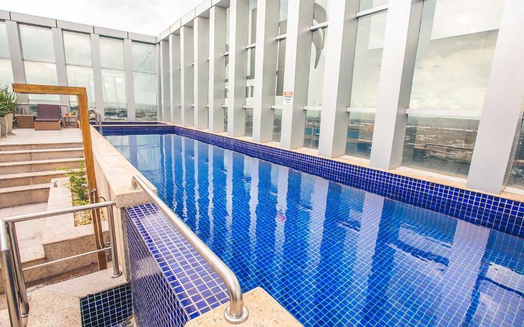 a large swimming pool in a building with windows at V1318 Lindo flat aconchegante em andar alto in Brasilia