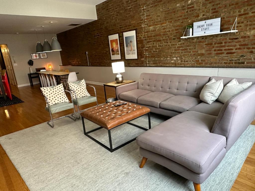 a living room with a couch and chairs and a brick wall at Trendy Wicker Park Loft with Parking in Chicago