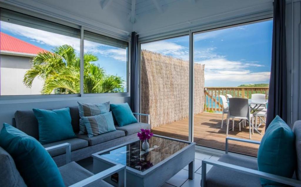 a living room with a couch and a large window at Saint Barth Villa 14 in Saint-Jean