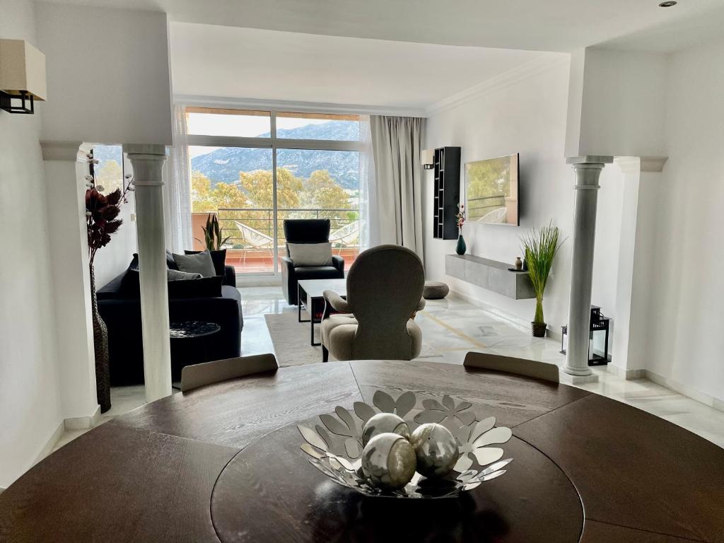 un soggiorno con tavolo e un soggiorno con divano. di Magna Marbella Golf Resort Apartment a Marbella