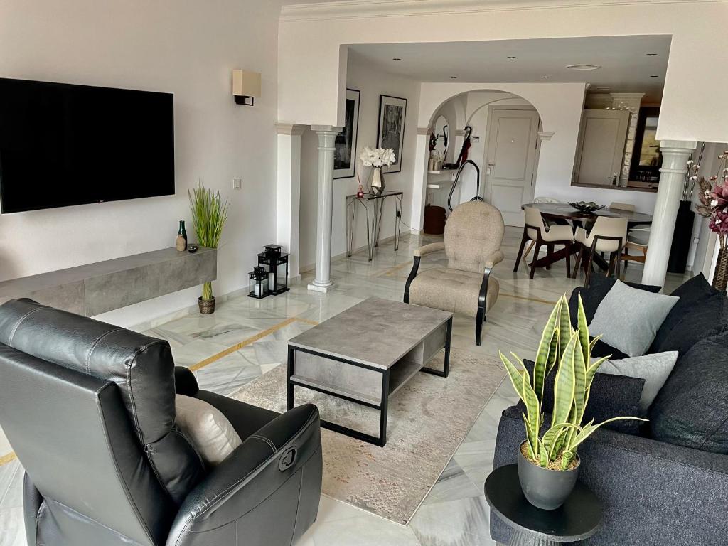 uma sala de estar com um sofá e uma televisão na parede em Magna Marbella Apartment em Marbella