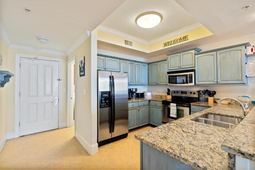 Una cocina con gabinetes azules y un refrigerador de acero inoxidable. en 503 Holiday Isle 503, en Dauphin Island
