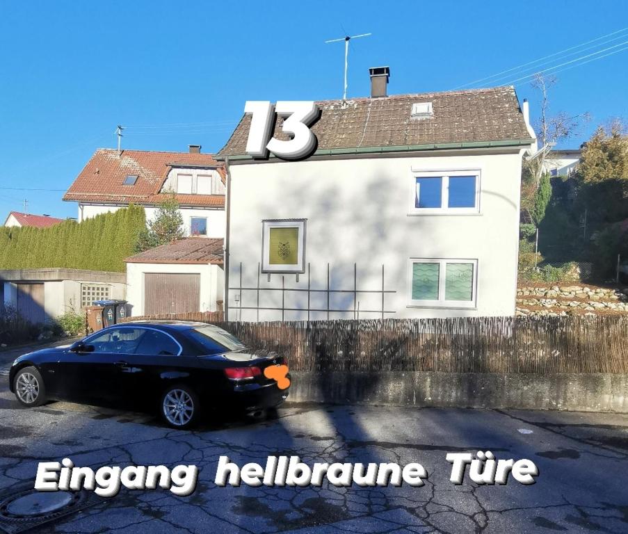 una macchina nera parcheggiata di fronte a una casa bianca di Privatzimmer in ruhiger Lage in Heidenheim/ Steinheim am Albuch a Steinheim am Albuch