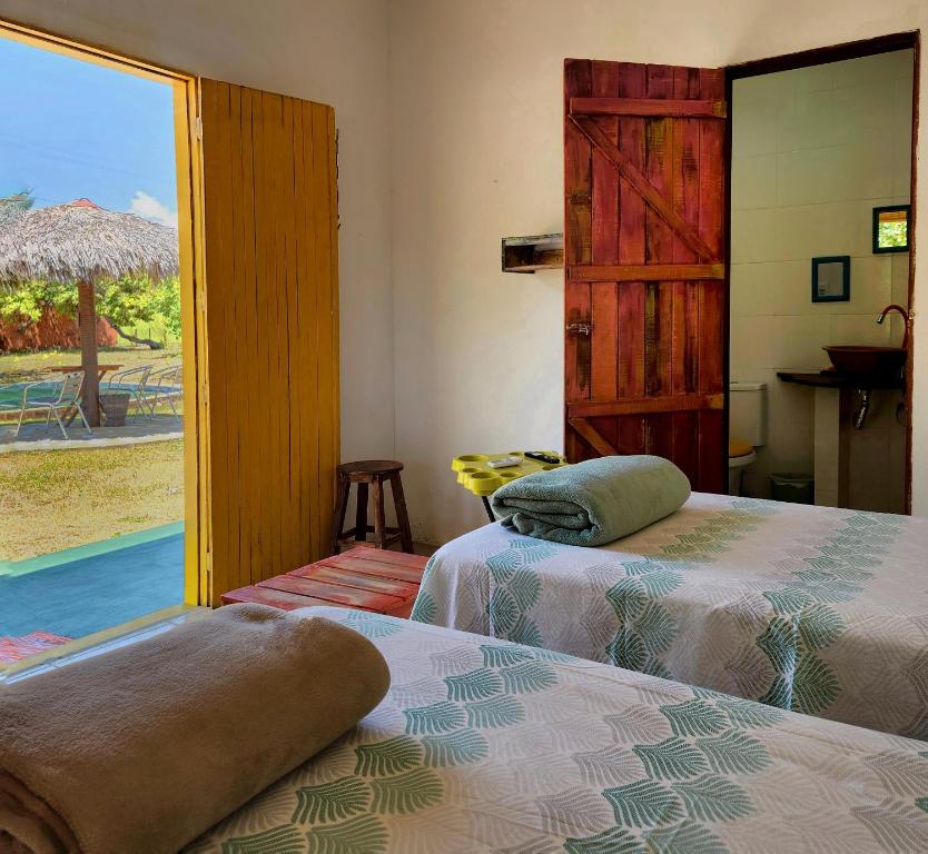 two beds in a room with a view of a pool at Sítio SPA Céu De Verdade , Praia de Barra Nova , Ceará in Cascavel