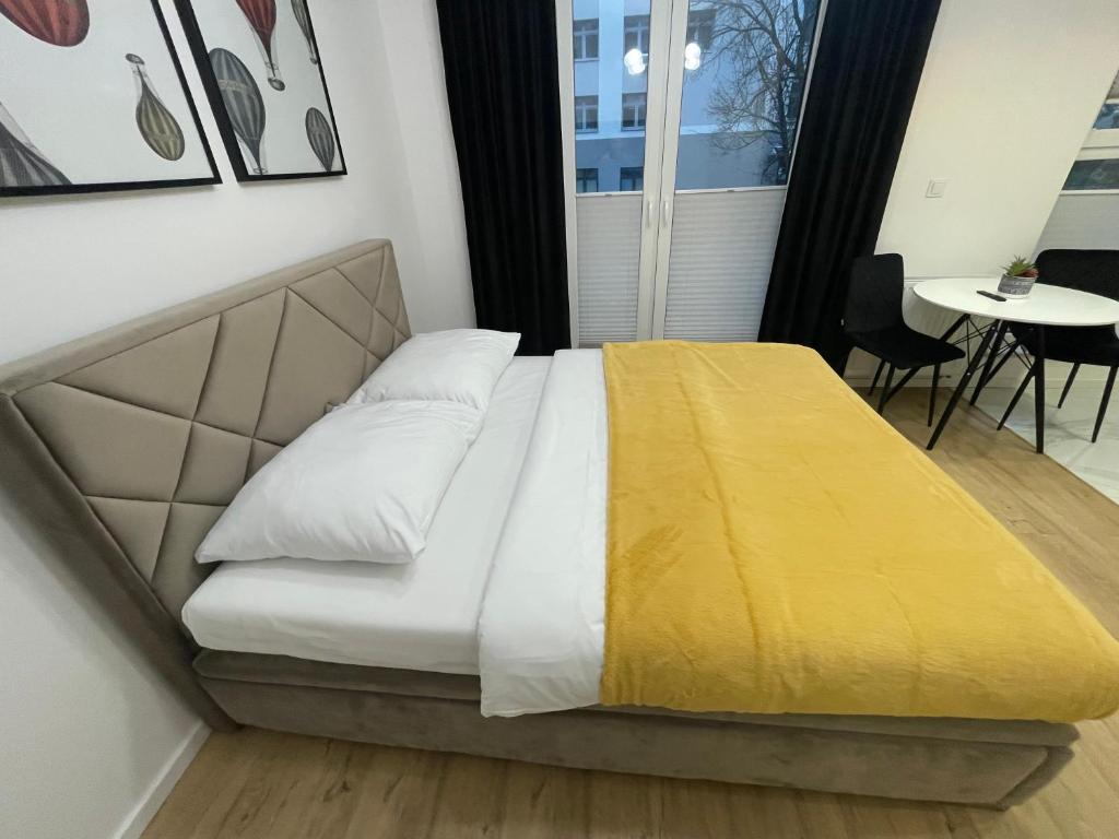 łóżko w pokoju z żółtym kocem w obiekcie Platinium Queen Aparthotel CENTRUM w Kielcach