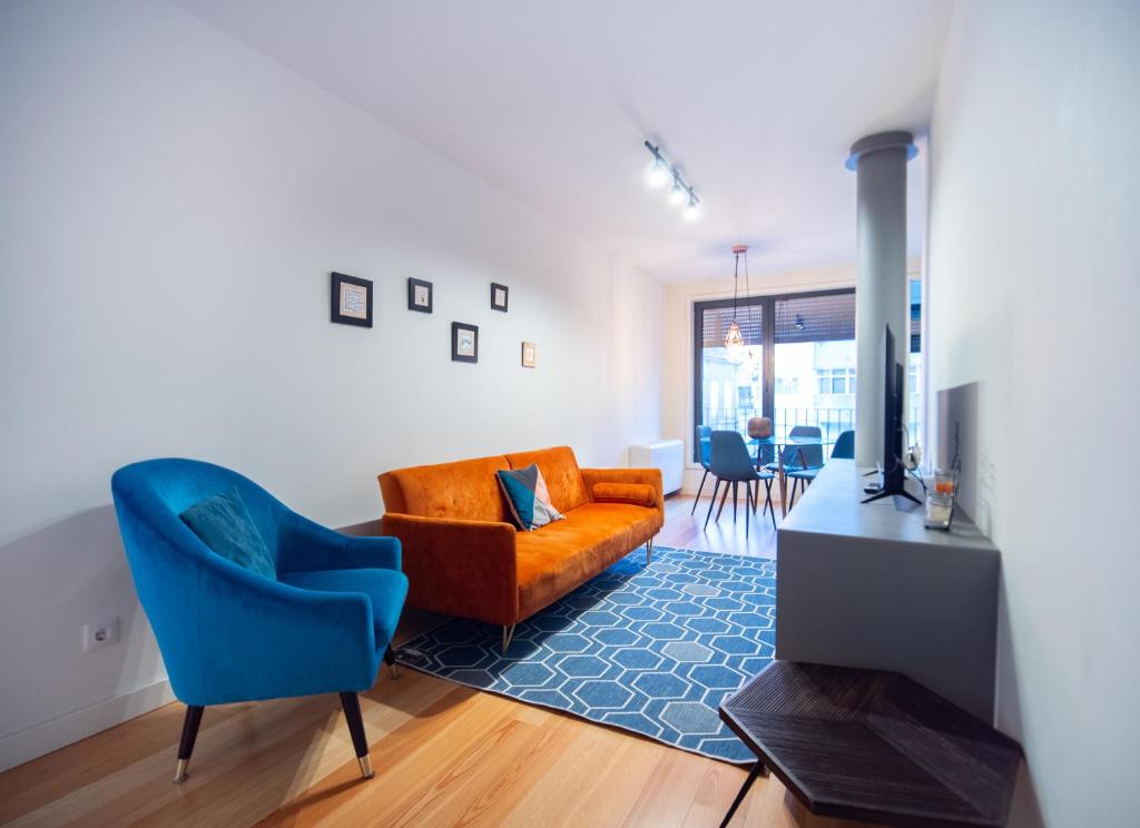 ein Wohnzimmer mit einem Sofa und einem blauen Stuhl in der Unterkunft Oporto City View - Alves da Veiga in Porto