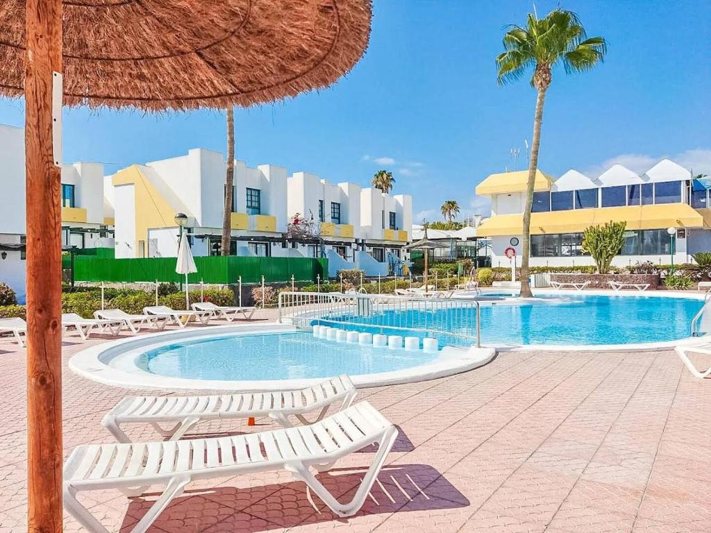 une piscine de villégiature avec des chaises et un parasol en paille dans l'établissement Andrea's Home, à San Bartolomé