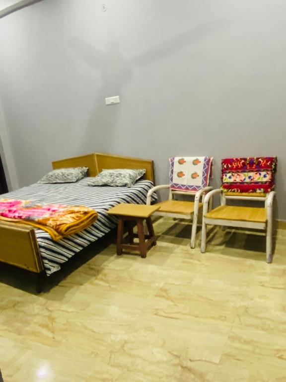 a room with two beds and two chairs in it at Dreams Stay in Lucknow