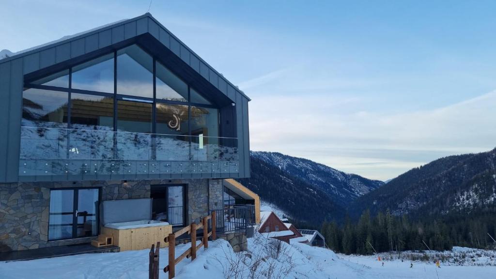a house in the snow with mountains in the background at Lucky Chalet Jasná in Demanovska Dolina