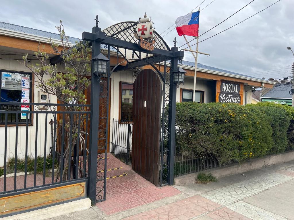a black gate with a flag in front of a house at HOSTAL VICTORIA in Punta Arenas