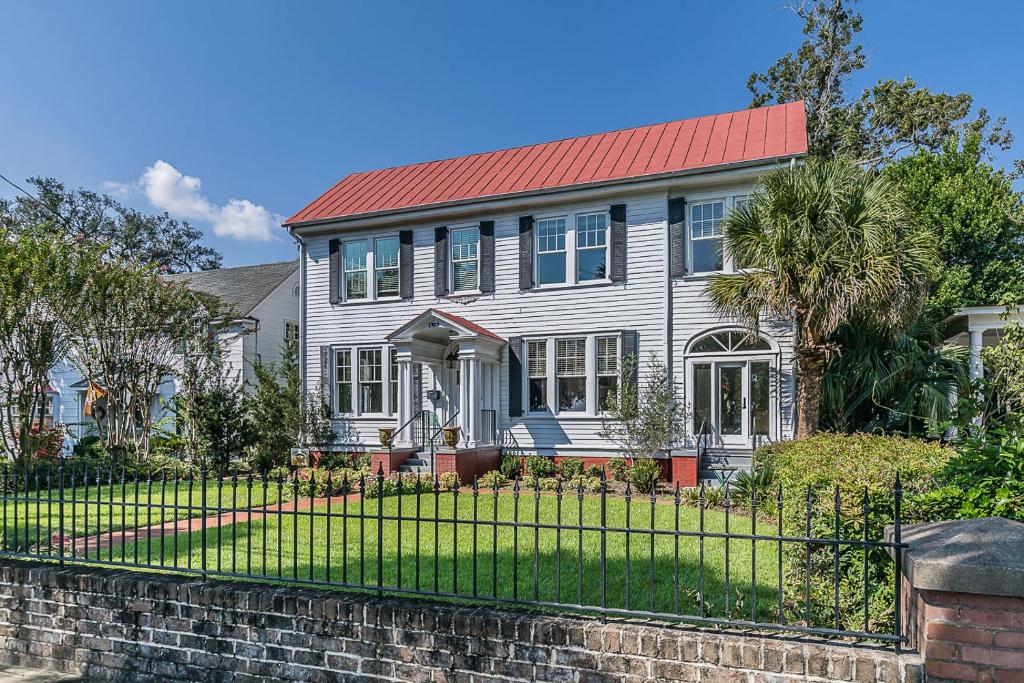 a house with a red roof and a fence at Historic Home Overlooking the Beaufort River Located on Bay St - Sleeps 10 in Beaufort