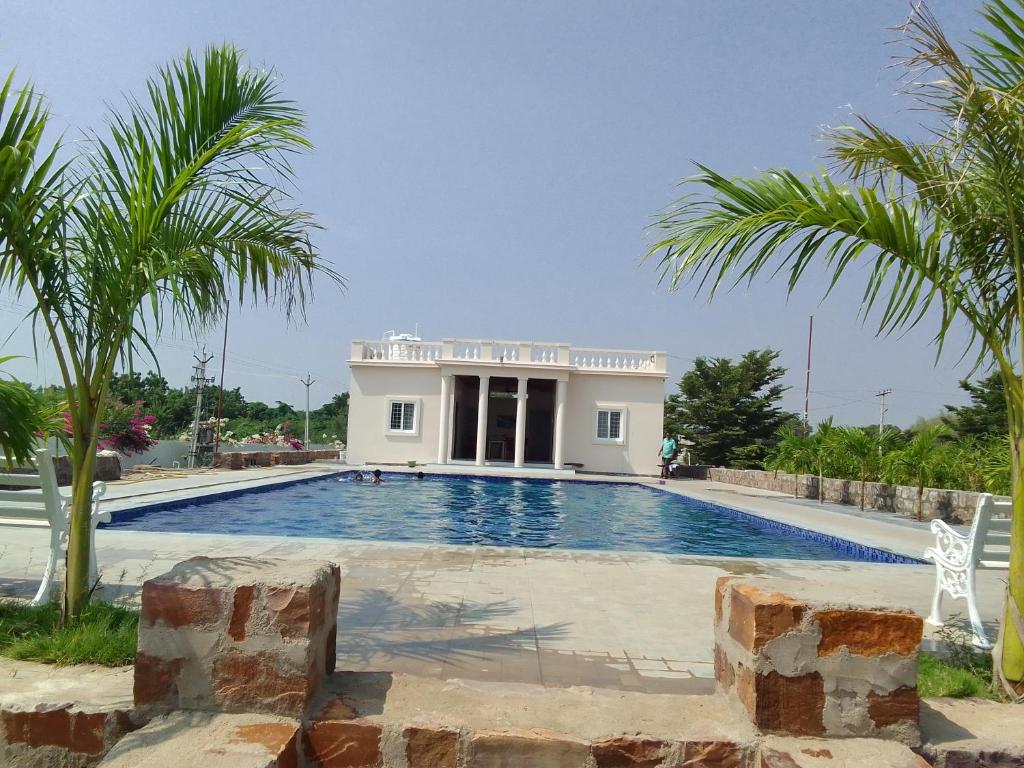 a villa with a swimming pool and palm trees at Rivera Resort- Night stay in Jammalamadugu