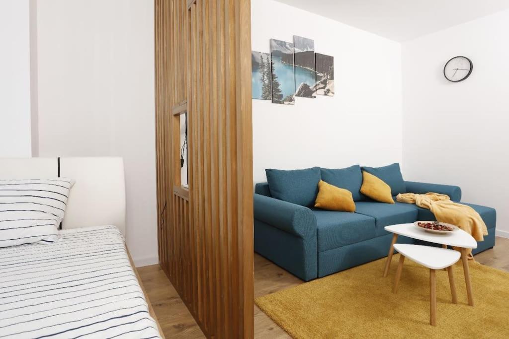 uma sala de estar com um sofá azul e uma mesa em Apartament Modern Ivory Pipera em Voluntari