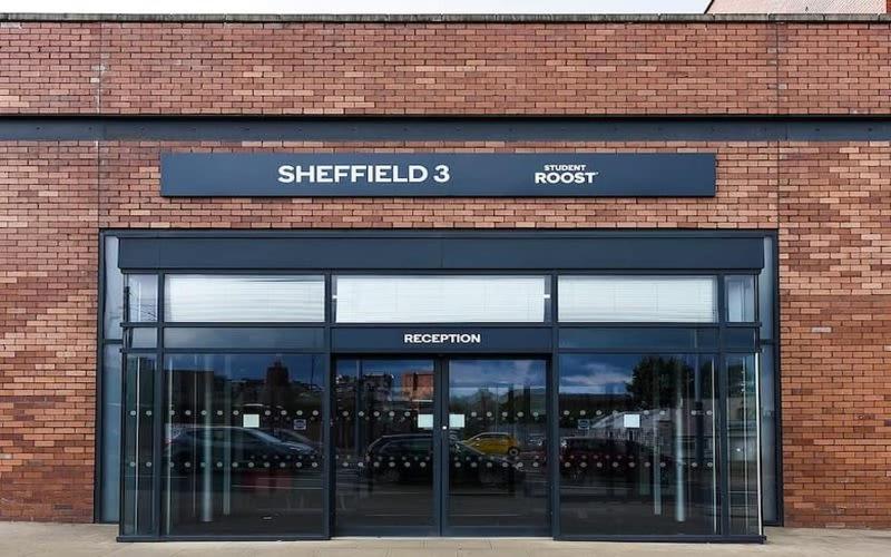 謝菲爾德的住宿－Cosy Modern Studios at Sheffield 3 located near the University of Sheffield，停车场内有汽车停放的砖砌建筑