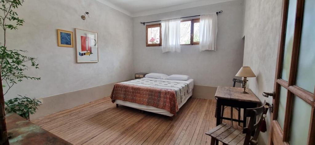 a bedroom with a bed and a table and windows at Domenica Casa Hotel in La Cumbre