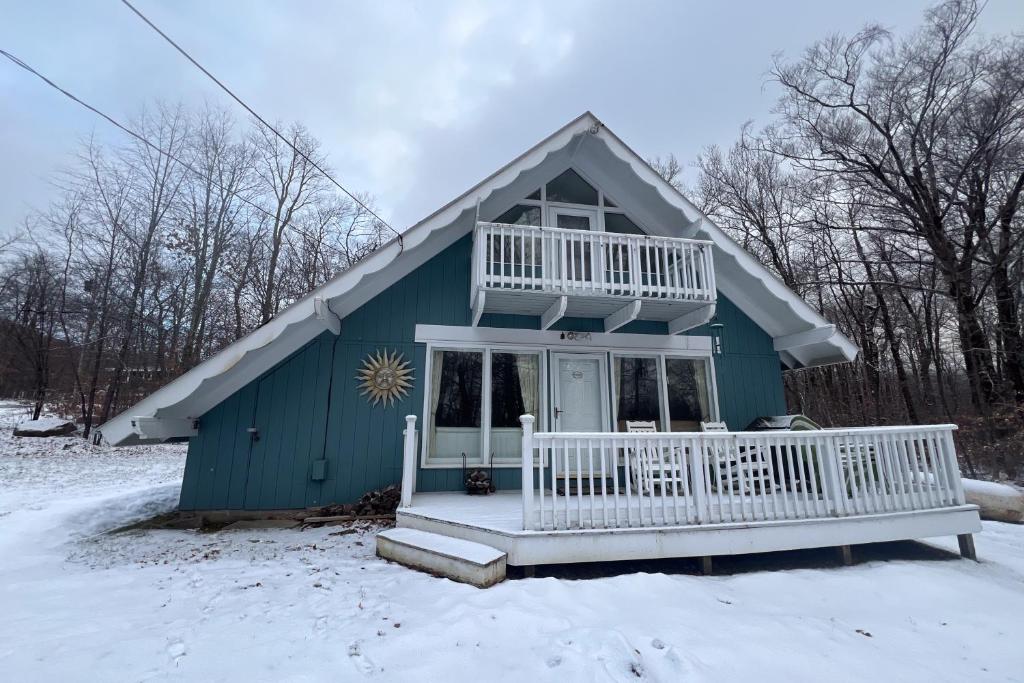 a blue house with a porch in the snow at Buzz's Place in Barnumville