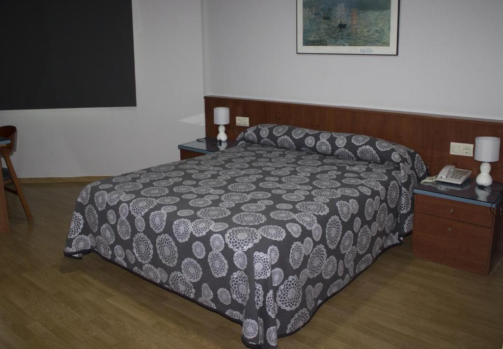a bedroom with a bed and a table with a phone at Hotel Costa Blanca in Granja de Rocamora