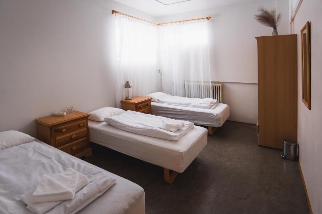 a room with three beds and a window at Studlagil INN Hostel in Skjöldólfsstaðir