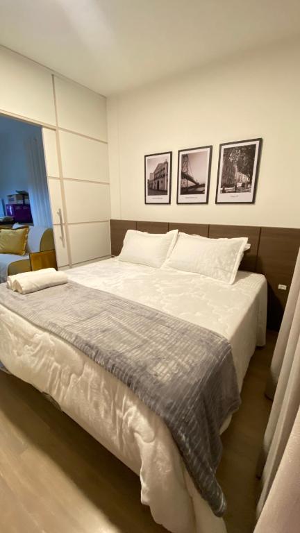 a bedroom with a large white bed with three pictures on the wall at Estúdio 198 in Florianópolis