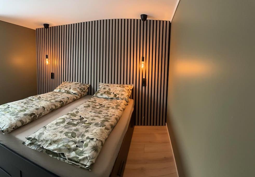 a bedroom with two beds and two lights on the wall at Familievennlig Apartment in Tvedestrand