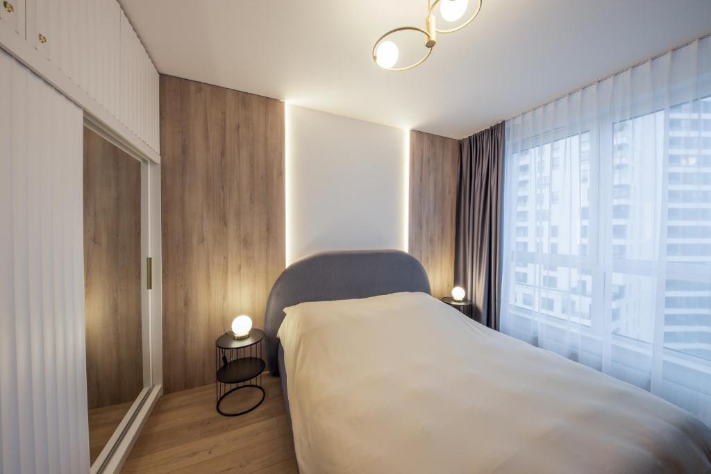 une chambre avec un lit et une grande fenêtre dans l'établissement Aperto Apartament Gdynia centrum 10 piętro, à Gdynia