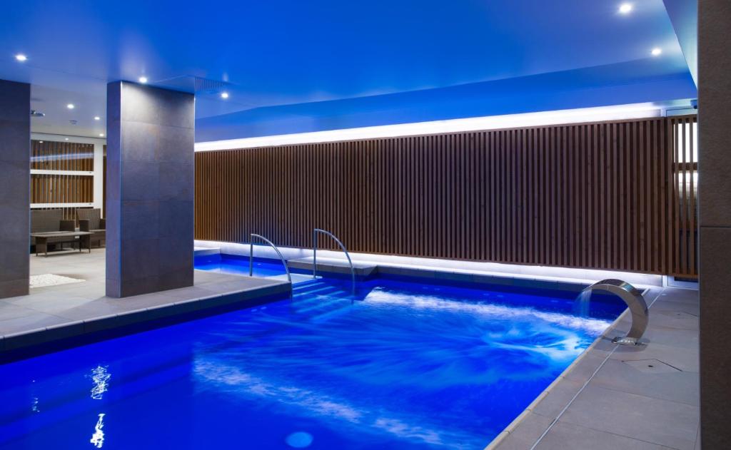 a pool in a hotel with blue lighting at Hôtel Le Rapp in Colmar